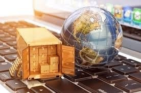 Golden globe sphere and wooden shipping container on a laptop keyboard, representing global trade and logistics